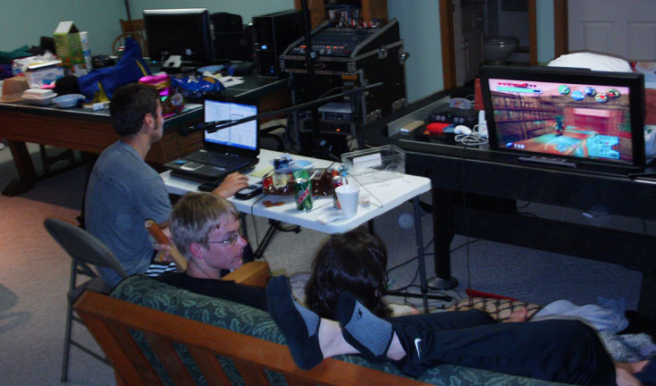 An event in 2010, showcasing a single laptop, game monitor, and a group of people on a couch